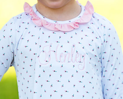 Children's outfit with floral pattern and pink ruffled collar on a yellow background