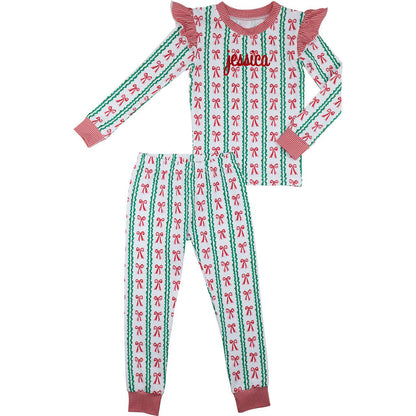 Children's pajama set with red and green bow pattern on a white background