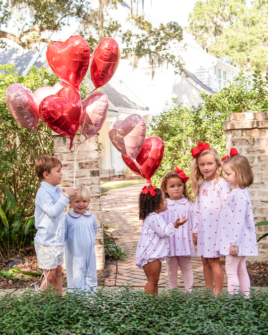 Children with heart-shaped balloons outdoors