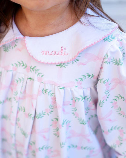 Close-up of a child's floral dress with 'madi' embroidered on the collar.