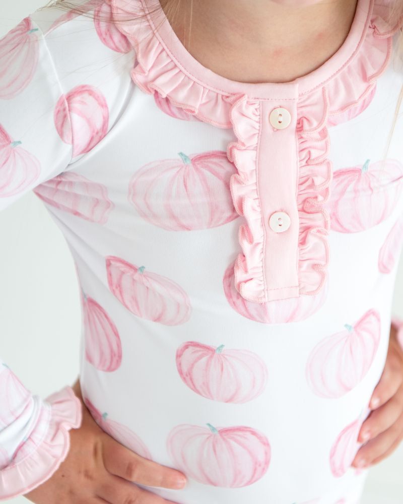 Close-up of a child's outfit with pink pumpkin pattern on a white background