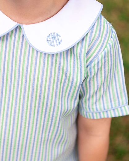 Close-up of a child's shirt with green and blue stripes and a white collar with monogram.