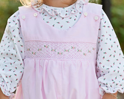 Close-up of a child wearing a pink long bubble with floral patterns.