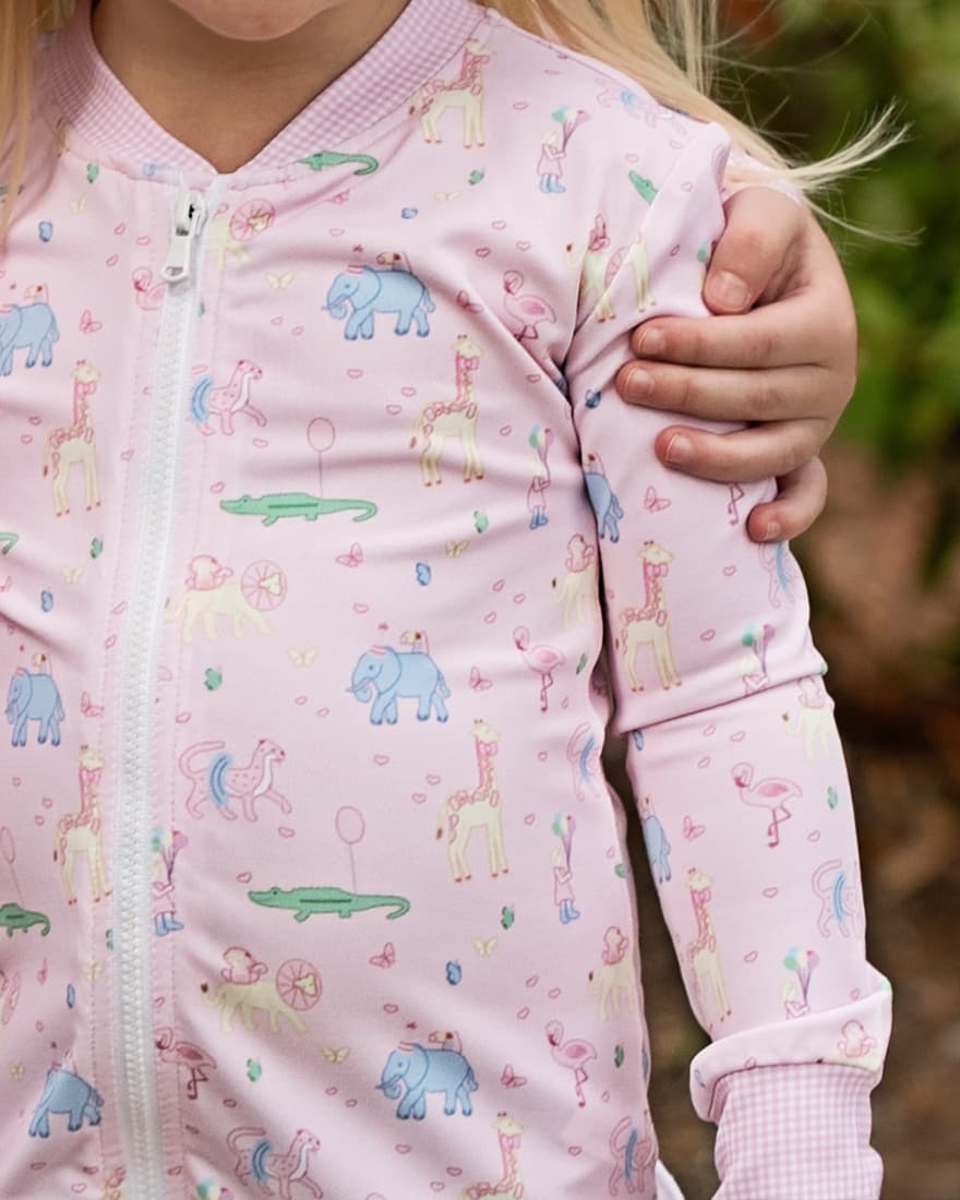 Close-up of a child wearing a pink pajama outfit with animal prints.