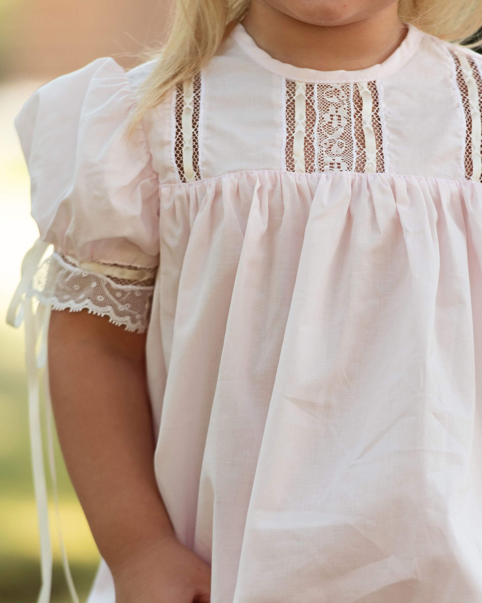 Close-up of a child wearing a white dress with lace details.