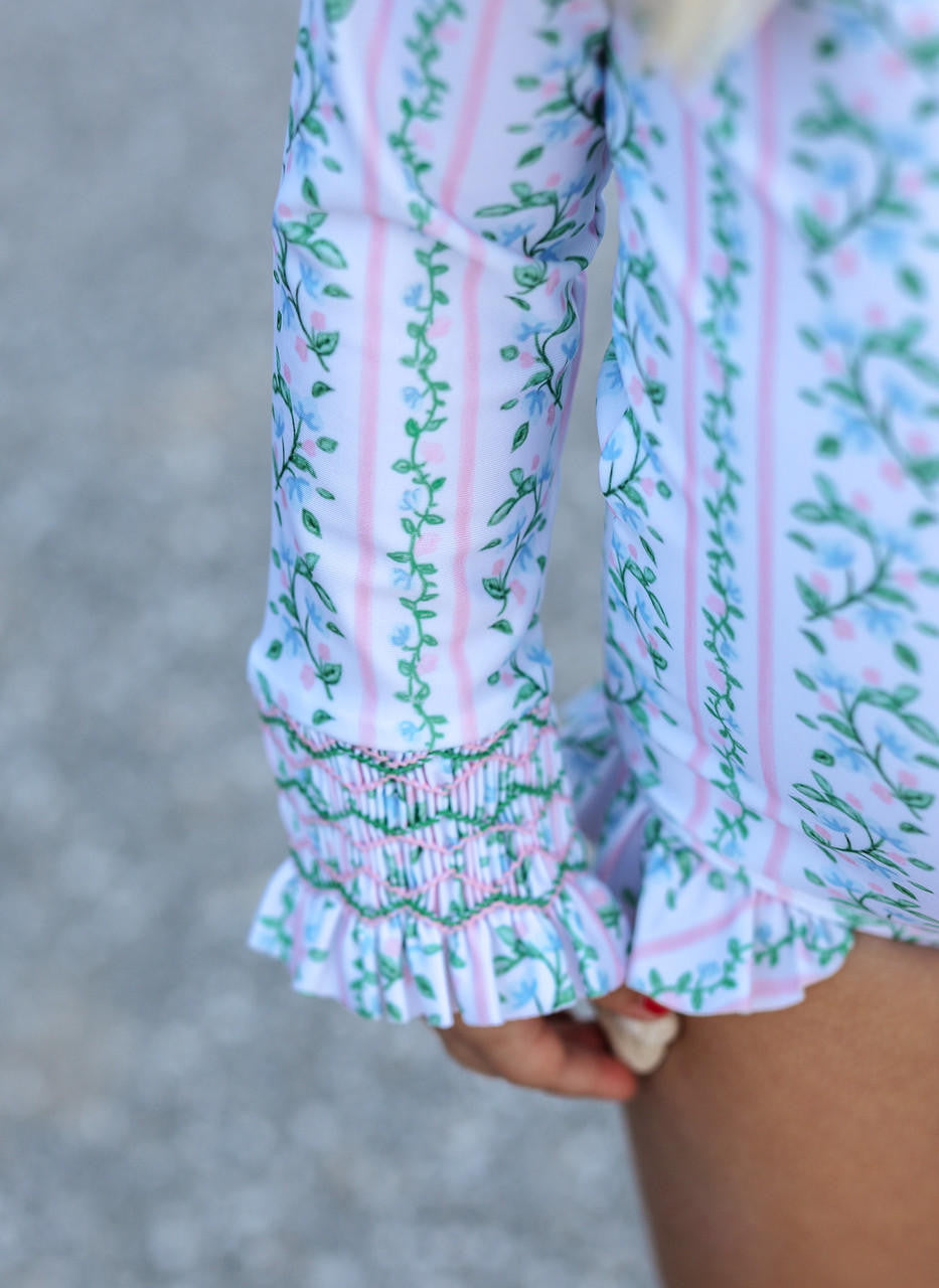 Close-up of a person wearing a patterned dress with smocked sleeves on a blurred background