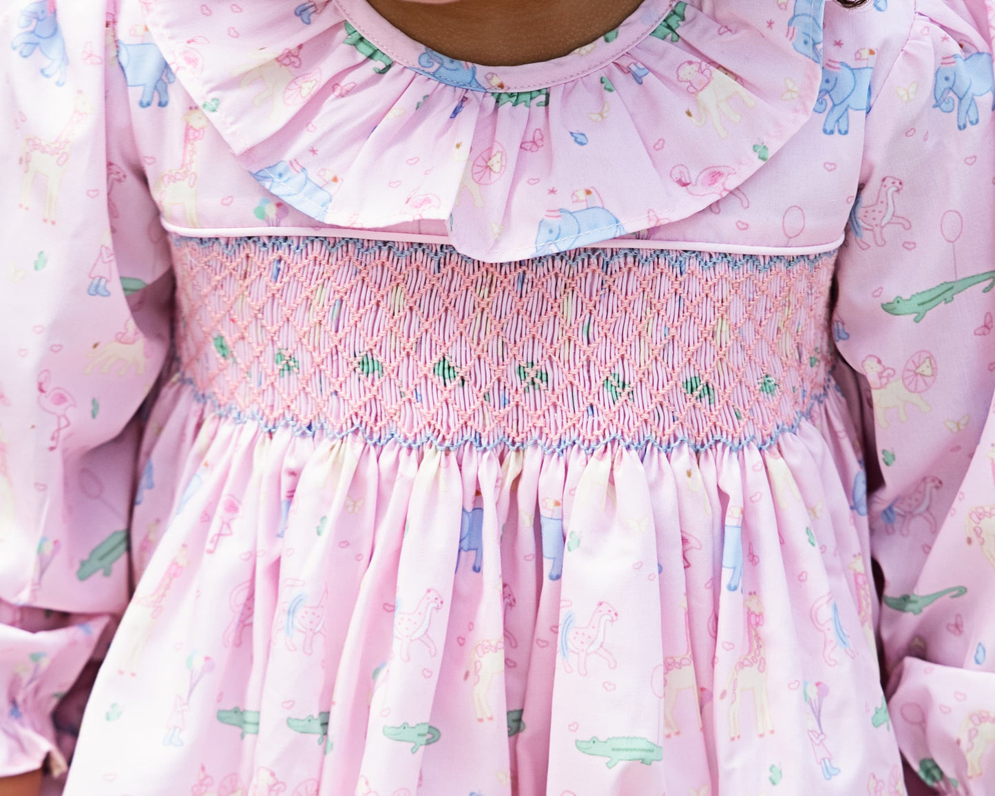 Close-up of a pink dress with ruffled collar and floral birthday pattern.