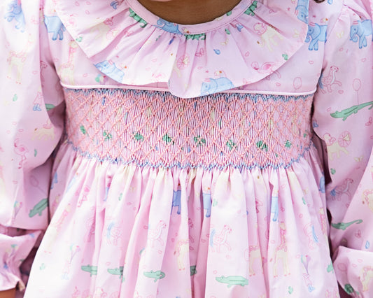 Close-up of a pink dress with ruffled collar and floral birthday pattern.