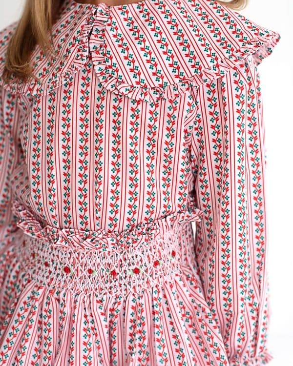 Close-up of a red and white floral patterned dress with long sleeves and smocked skirt.