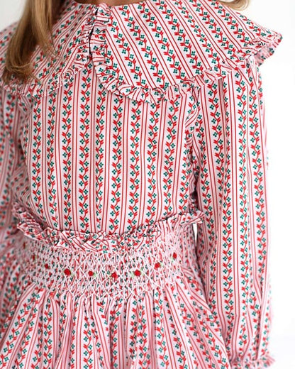 Close-up of a red and white floral patterned dress with long sleeves and smocked skirt.