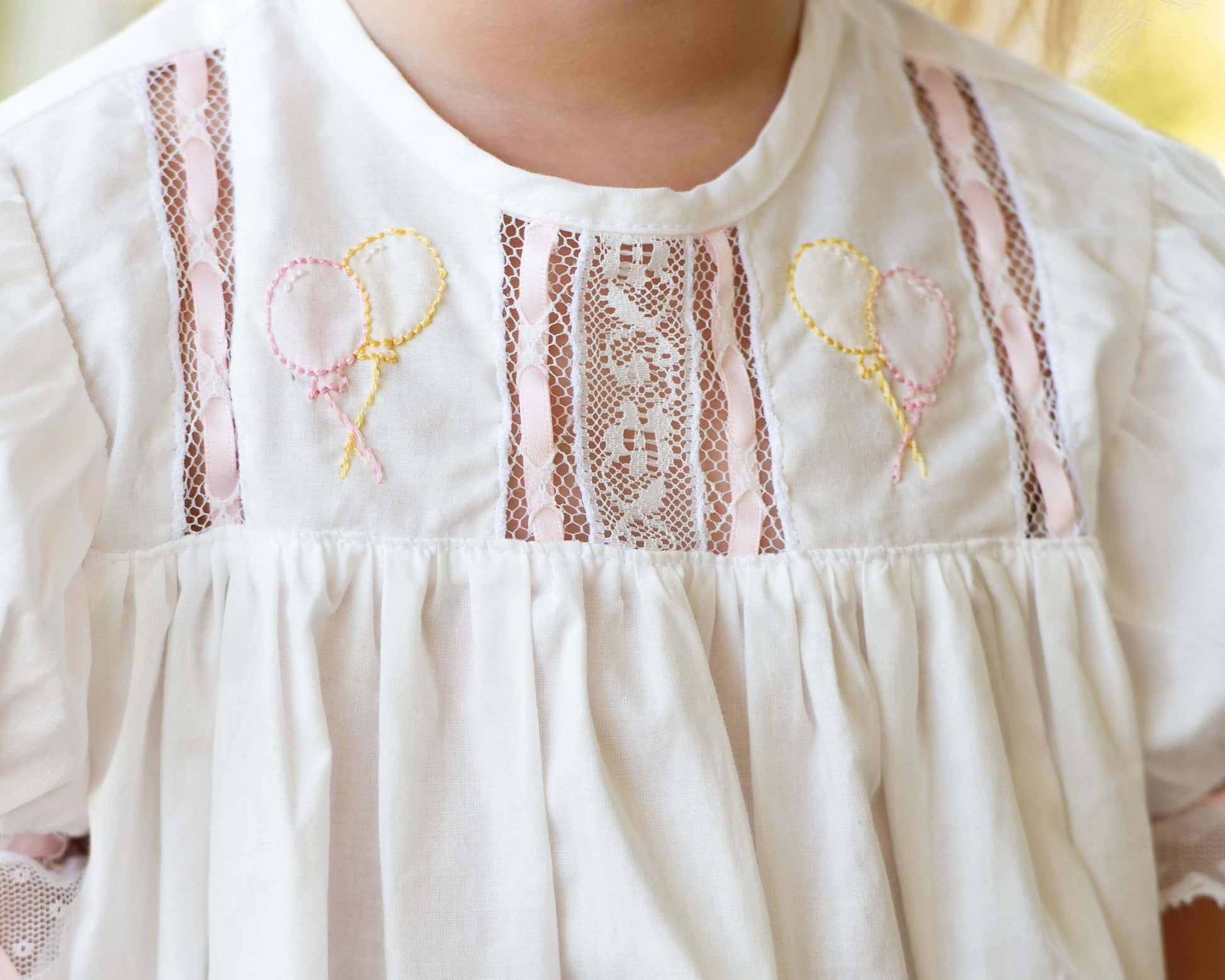 Close-up of a white dress with lace details and embroidered designs.