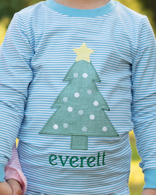 Close up of a child wearing Blue striped pajamas with an applique Christmas tree and a monogram
