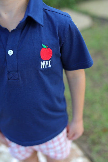 Close up of a navy polo shirt with an apple and initials embroidered.