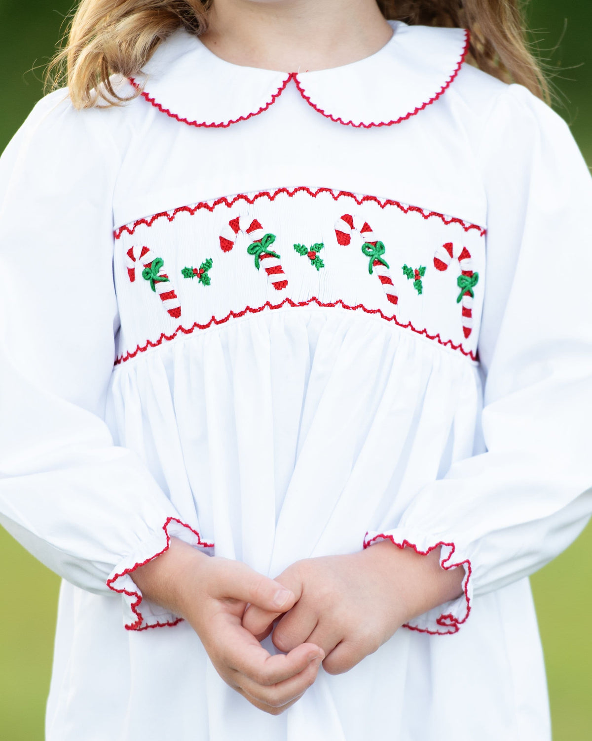 Close-up of Smocked Candy Cane Dress with candy cane, green bow, and holly smocking