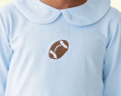 Closeup of a crochet football on a blue gingham top