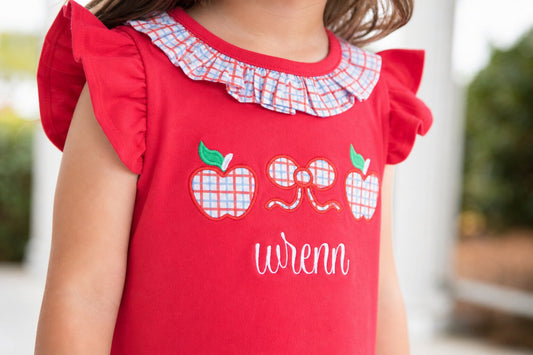 Closeup of a red shirt with applique apples and bow