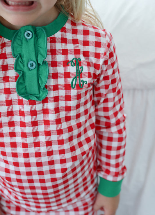 Closeup of red check pajamas with green accents and a single letter monogram on the chest