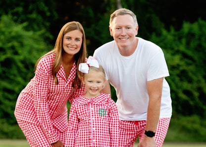 Family standing outside wearing matching red and white checked pajamas