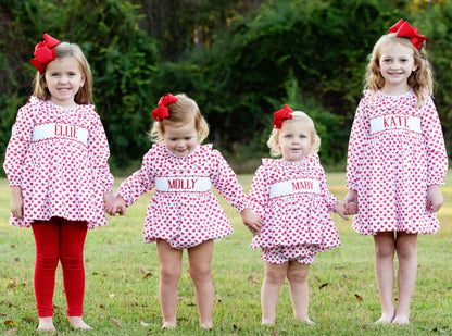 Four girls in matching Valentine outfits with red bows, standing outdoors