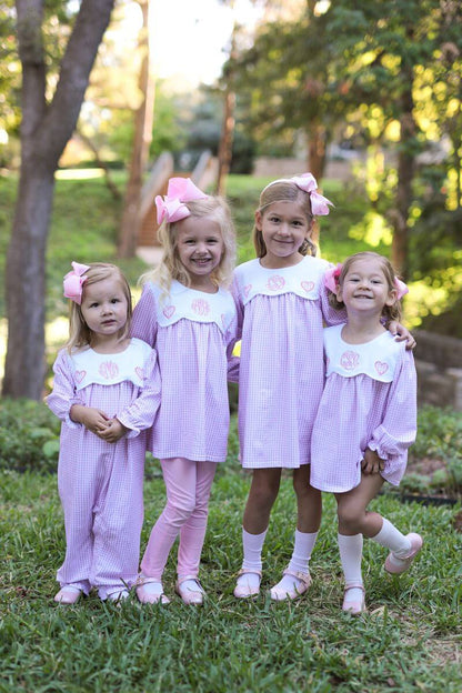 Four young girls in matching dresses standing outdoors with trees in the background