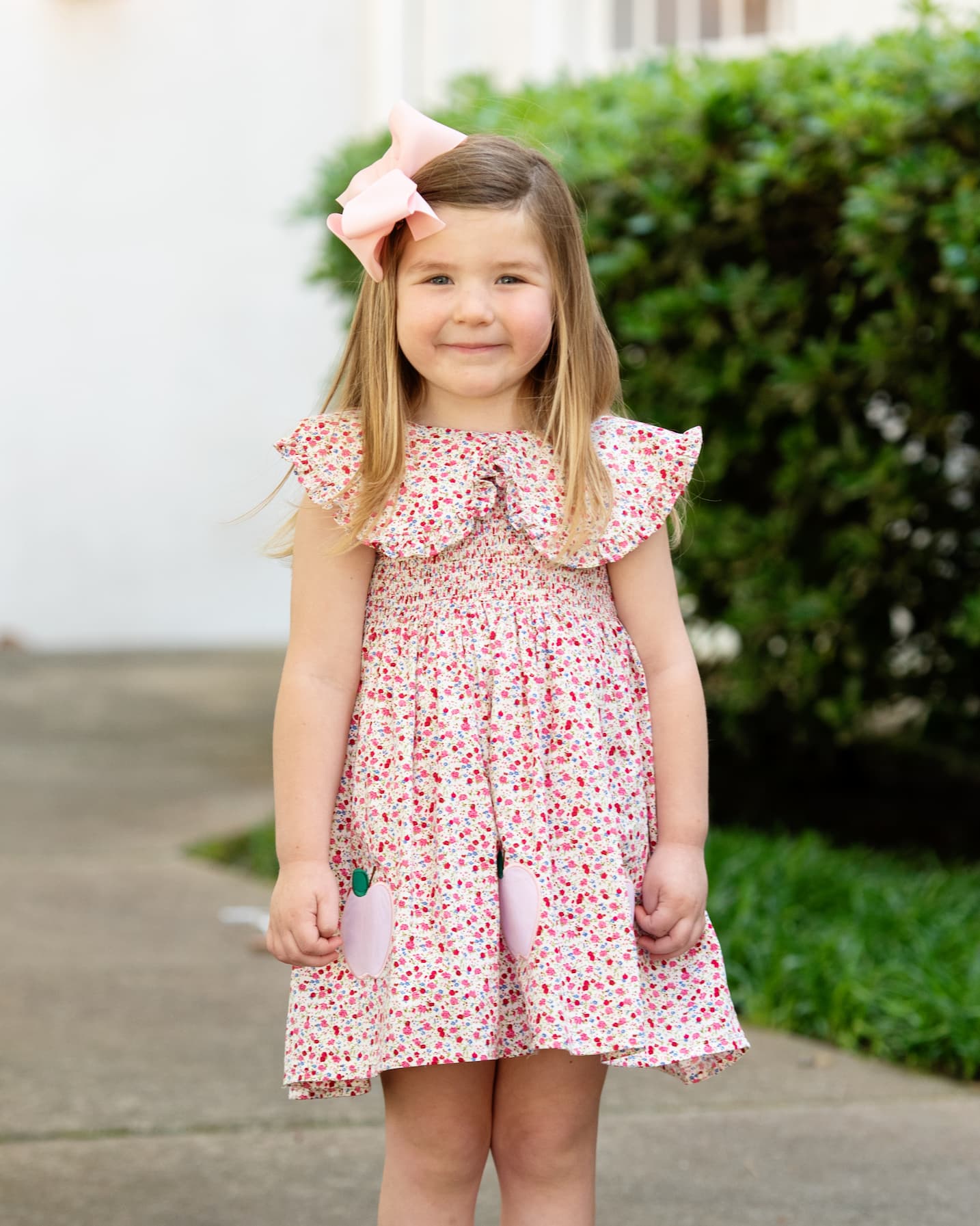 Girl in a floral dress with apples on it. 