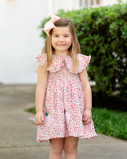 Girl in a floral dress with apples on it. 