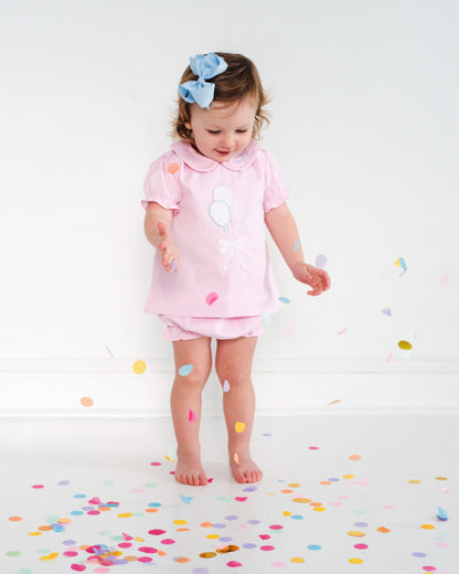 Girl in balloon outfit playing with confetti. 