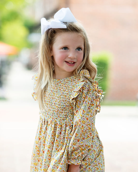 Girl in yellow floral dress and white bow