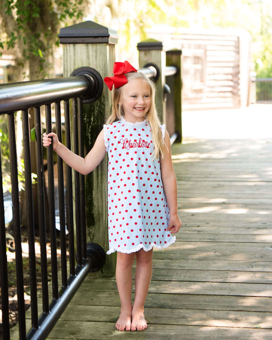 Girl standing on a bridge wearing an apple print dress and a red bow