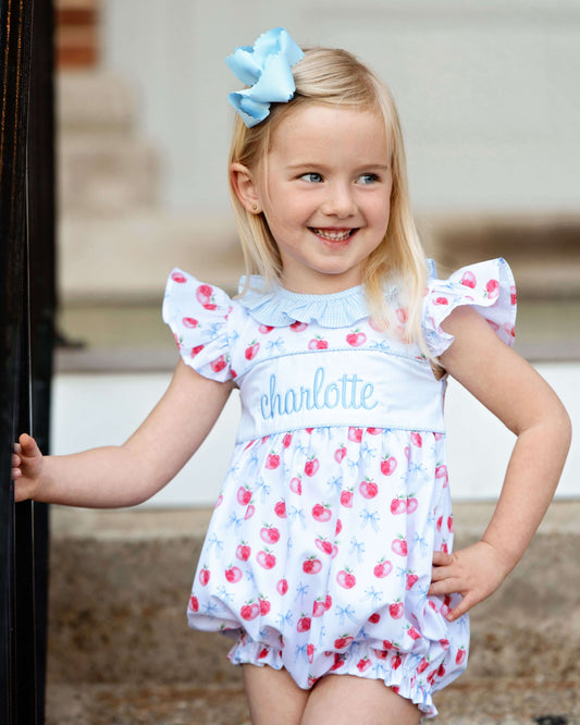 Girl standing with hand on hip in a bow and apple print bubble. 