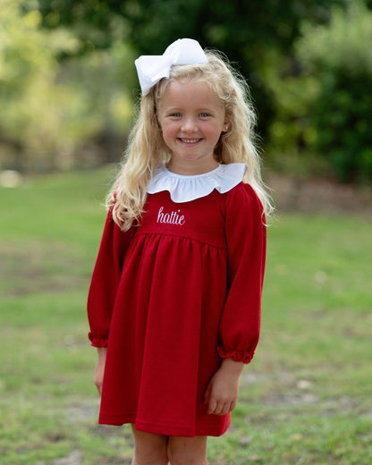 Girl with blonde hair wearing a red dress with a white bow
