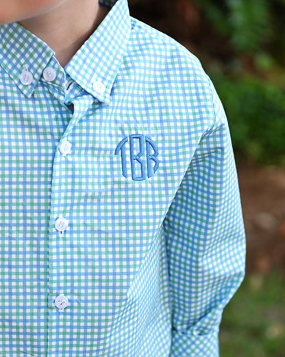 Green and blue checkered shirt with monogram on a blurred outdoor background