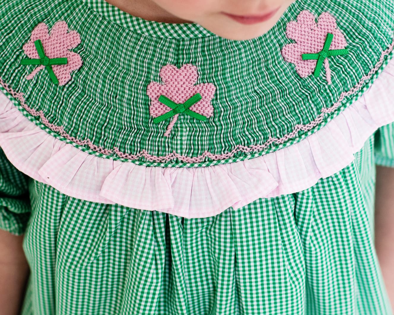 Green checkered dress with pink floral embroidery on a child