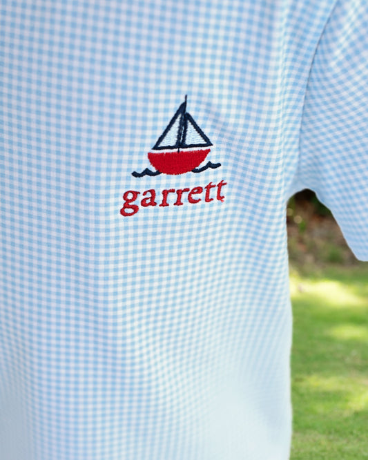 Light blue checkered shirt with a red sailboat design and 'garrett' monogram.