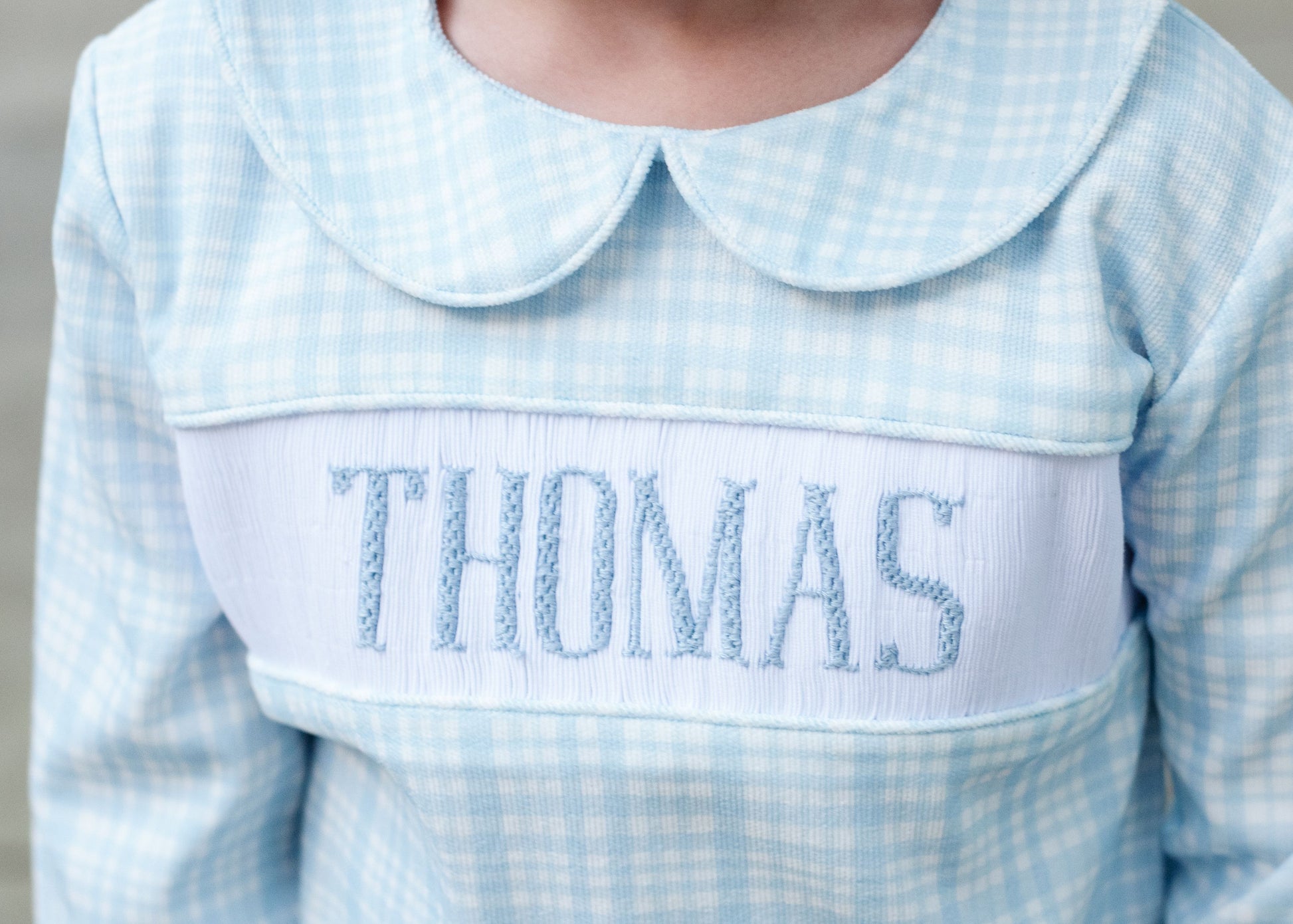 Light blue checkered shirt with embroidered name 'THOMAS' on a plain background