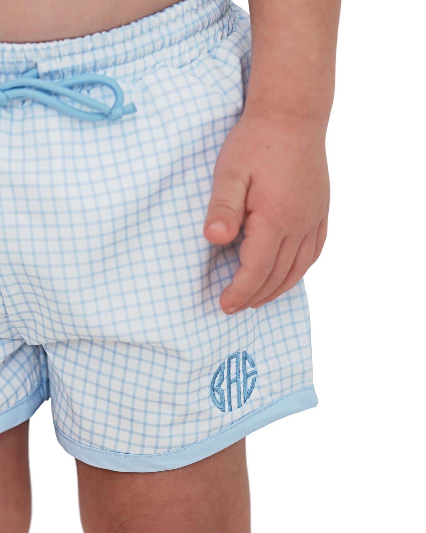Light blue checkered shorts with a monogram on a white background
