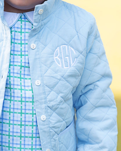 Light blue quilted jacket with monogram on a yellow background