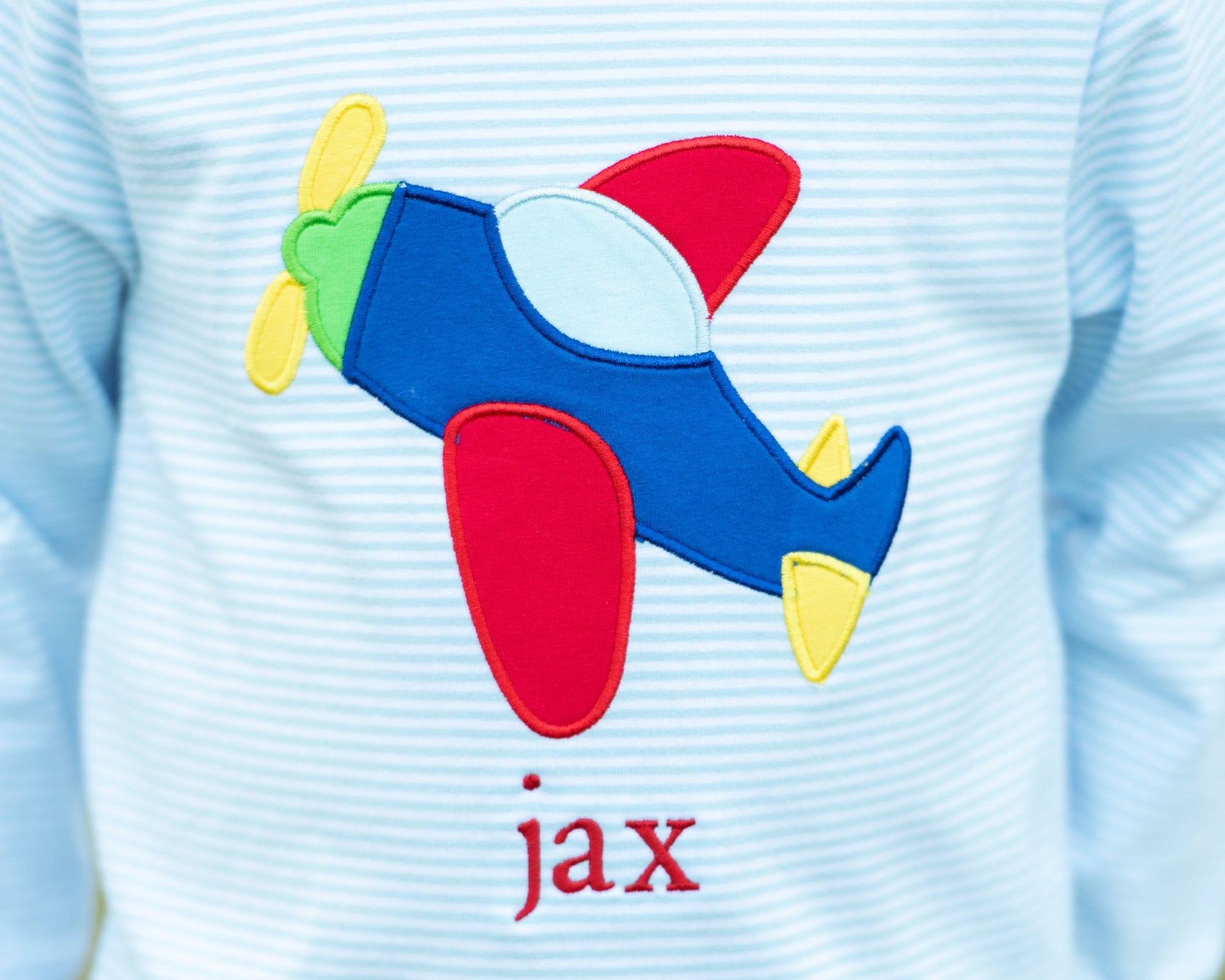 Light blue shirt with a colorful airplane patch and 'jax' text
