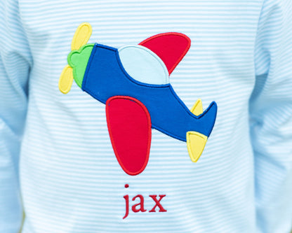 Light blue shirt with a colorful airplane patch and 'jax' text