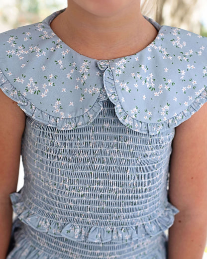 Light blue smocked skirt set with floral collar worn by a child