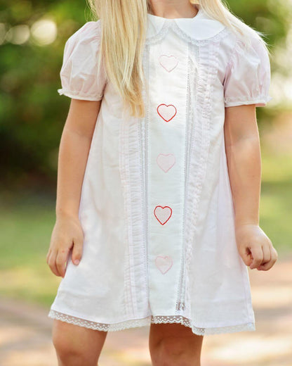 Light pink dress with heart patterns worn by a child outdoors
