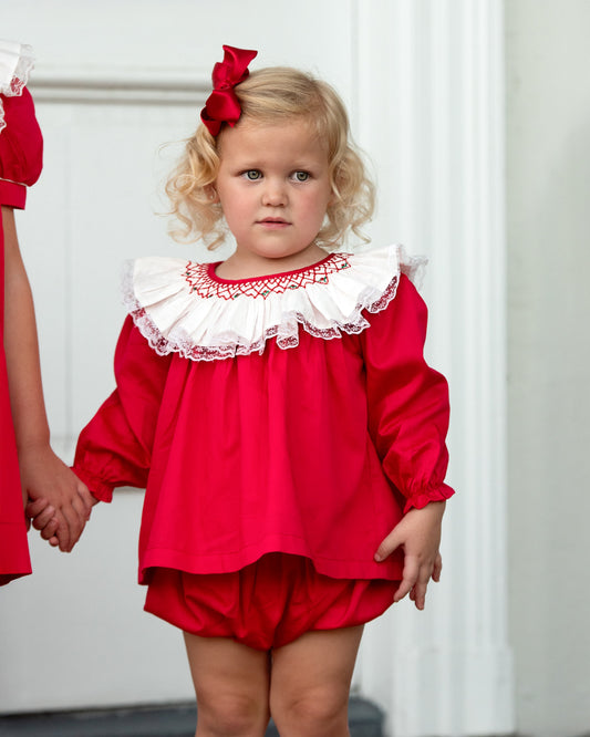 Little girl wearing a red diaper set with an oversized lace neckline with detailed smocking