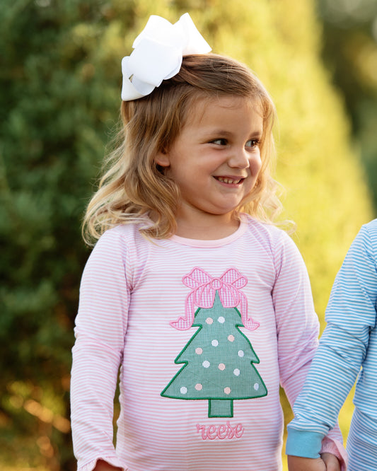 Little girl wearing pink striped Christmas tree pajamas