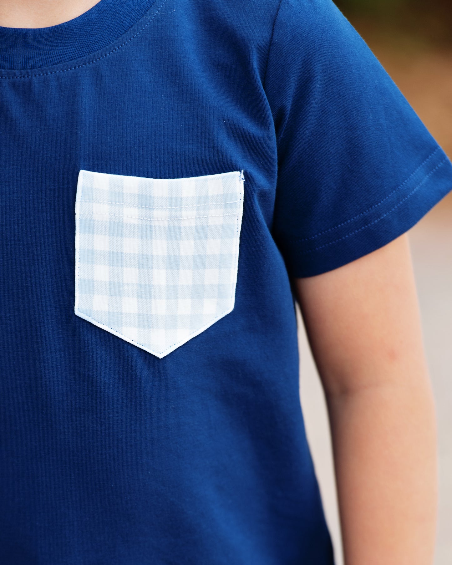 Navy blue t-shirt with a white checkered pocket on a blurred background