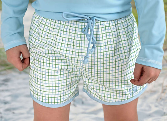 Person wearing green checkered shorts with a blue drawstring on a beach.