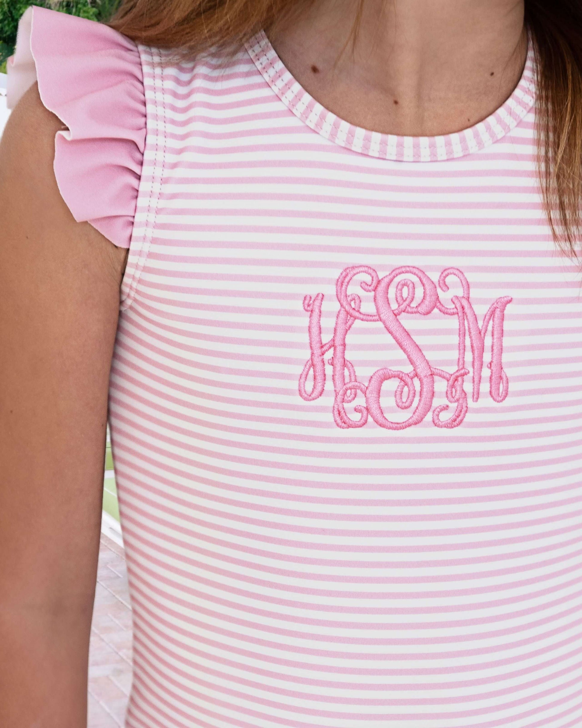 Pink and white striped tank top with embroidered initials on a person.