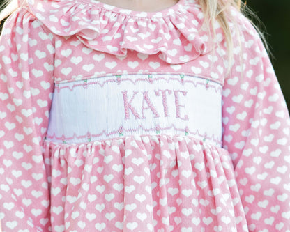 Pink heart dress with white heart pattern and 'KATE' smocking
