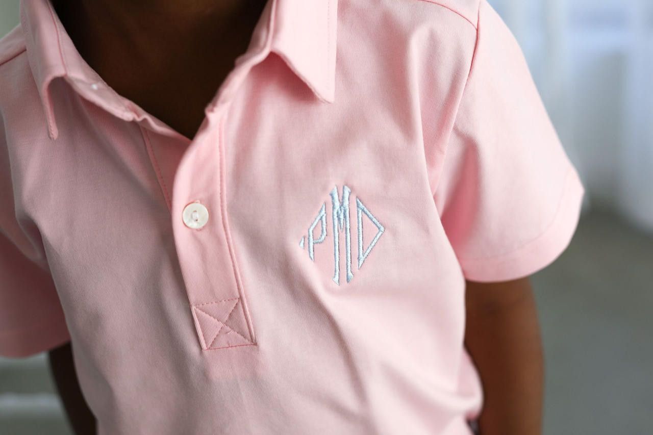 Pink polo shirt with monogram on a blurred background