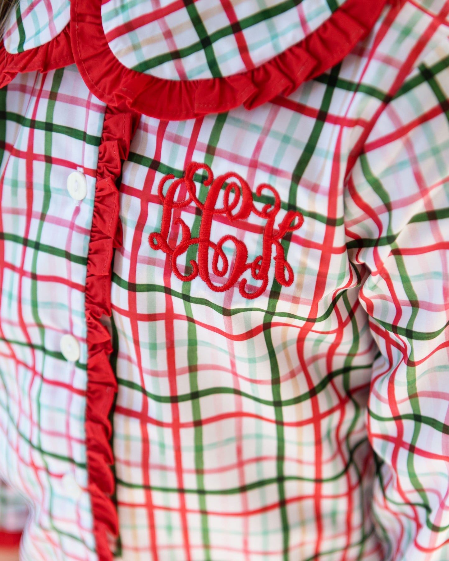 Plaid garment with red trim and embroidered text on a white background