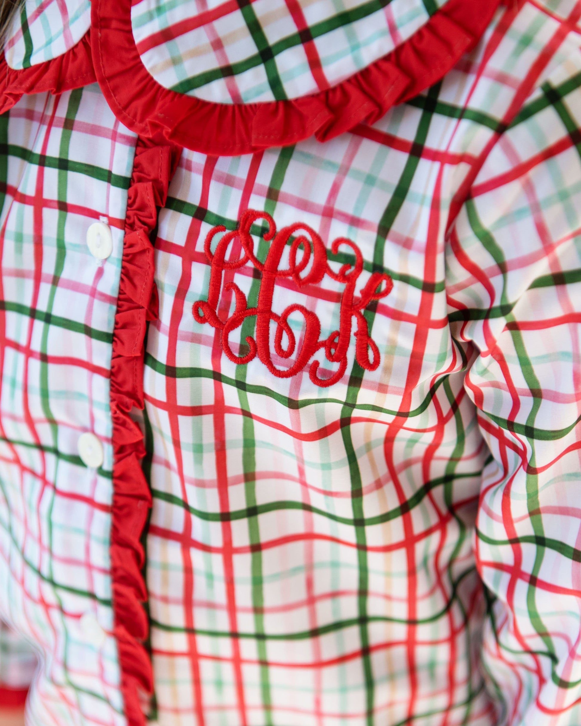 Plaid garment with red trim and embroidered text on a white background